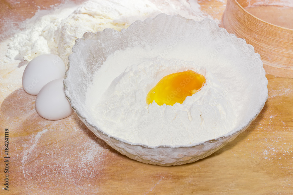 Broken egg in bowl with flour and two whole eggs Broken egg in bowl with flour and two whole eggs