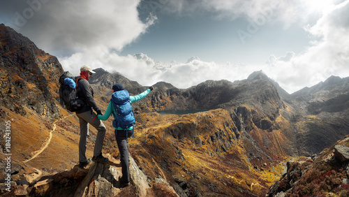 Two Hikers with backpacks in mountains enjoying panoramic on view of mountains