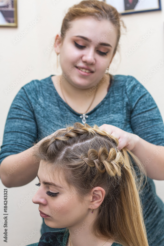 Naklejka premium A vertical crop shot of haircutting by pretty barber in a beauty salon