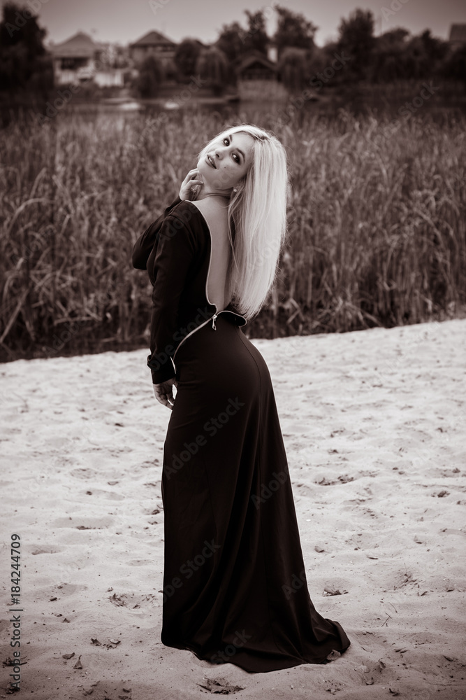 Naklejka premium Fashionable girl in a long blue dress in the evening against a background of nature. The concept of female beauty and elegance in fashion and style