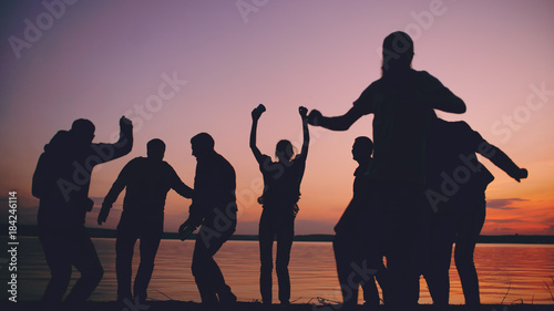 Photography Silhouette of Group young dancing people have a party at beach on sunset