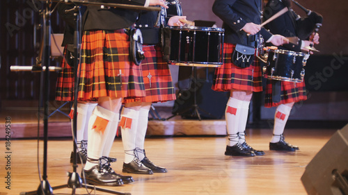 Traditional scottish band musicians singing with bagpipes and drums on the stage