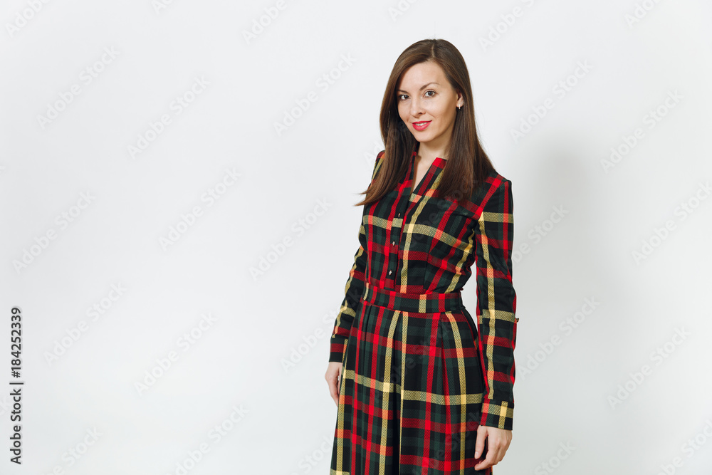 Beautiful European young happy brown-haired woman with healthy clean skin, dressed in long plaid checkered dress looking at camera with shy charming smile, on a white background. Holiday concept. Beautiful European young happy brown-haired woman with healthy clean skin, dressed in long plaid checkered dress looking at camera with shy charming smile, on a white background. Holiday concept.