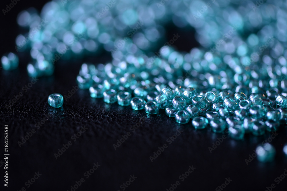 Scattered seed beads aquamarine color on a dark surface close up Scattered seed beads aquamarine color on a dark surface close up