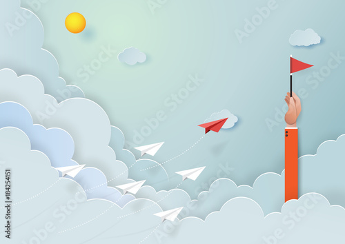 Paper airplanes flying on blue sky to the target of red flag on hand of businessman.Paper art style of start up and business teamwork creative concept idea.Vector illustration