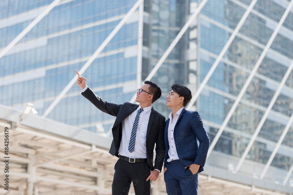 Successful two businessman in suit standing a being pointing finger in city looking go big city buildings, planning new projects, waiting for meeting to start. Copy space for text Successful two businessman in suit standing a being pointing finger in city looking go big city buildings, planning new projects, waiting for meeting to start. Copy space for text