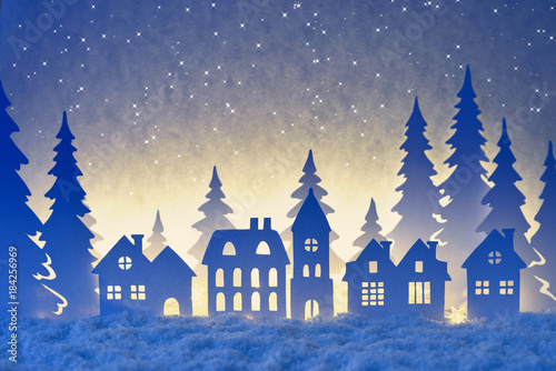 Silhouettes of a small village at winter time in the night. With stars in the sky.  Winter landscape made from paper.