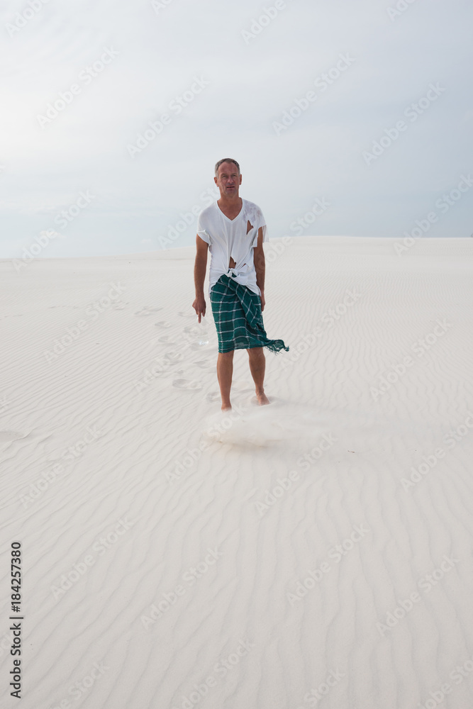 Exhausted man, lost in the desert, is walking along the dune