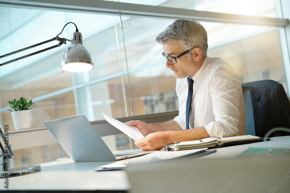 Businessman in office working at desk on laptop computer Businessman in office working at desk on laptop computer