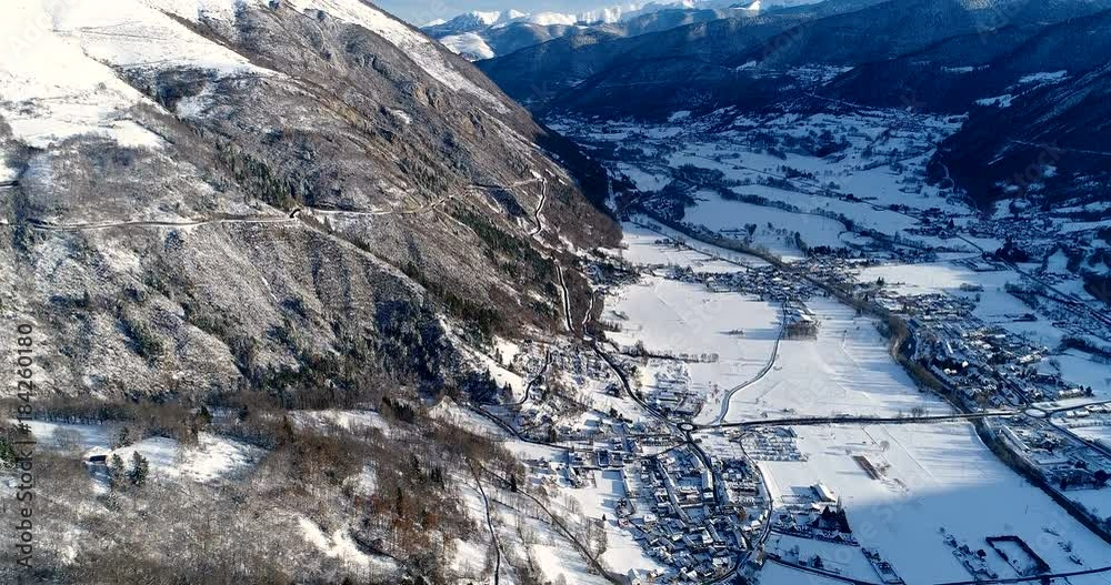 Vue aérienne d'une ville en bas d'une montagne couvert de neige - hiver paysage vallée ciel soleil nuage maison roche arbre vacance voyage