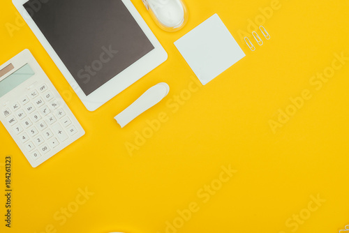 top view of digital tablet with blank screen, calculator and office supplies isolated on yellow photo