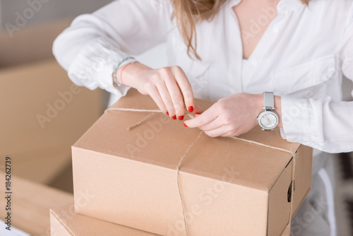 cropped shot of entrepreneur packing customers purchase in cardboard boxes at home office
