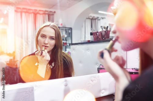A young girl does make-up in a beauty salon. The girl in front o