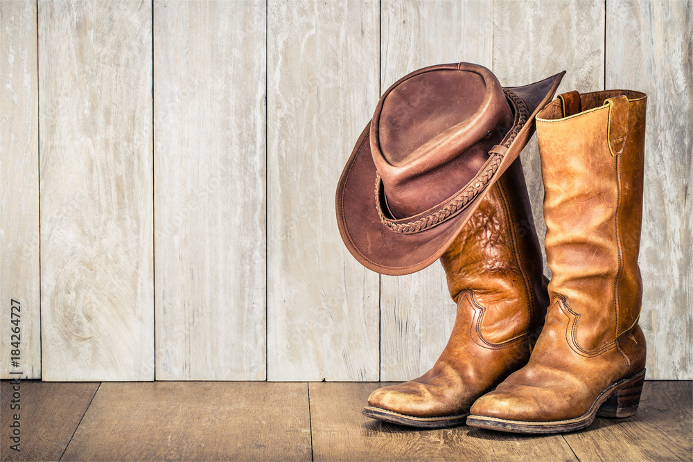 Wild West retro cowboy hat and pair of old leather boots on wooden floor.  Vintage style filtered photo Stock-Foto | Adobe Stock