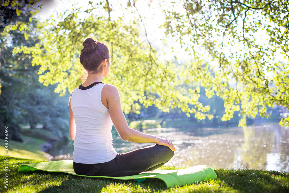 Young woman doing yoga in morning park near lake Young woman doing yoga in morning park near lake