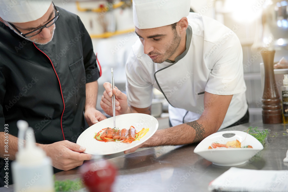 Professional cook chefs in kitchen improving dish composition Professional cook chefs in kitchen improving dish composition