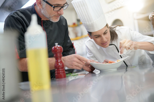 Professional cook chefs in kitchen improving dish composition