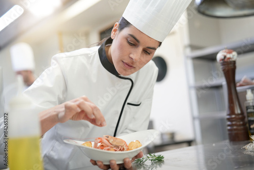 Fototapeta Closeup of cook chef in professional kitchen preparing dish
