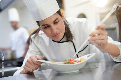 Professional cook garnishing plate in restaurant kitchen
