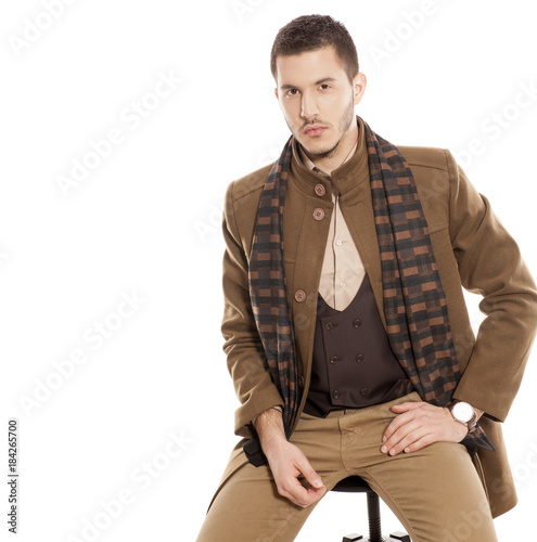 young handsome man in winter clothes with a scarf on white background photo