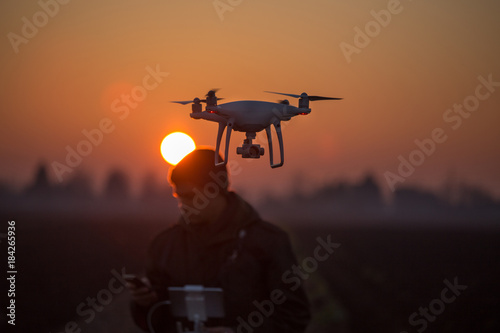Farmer navigating drone above farmland