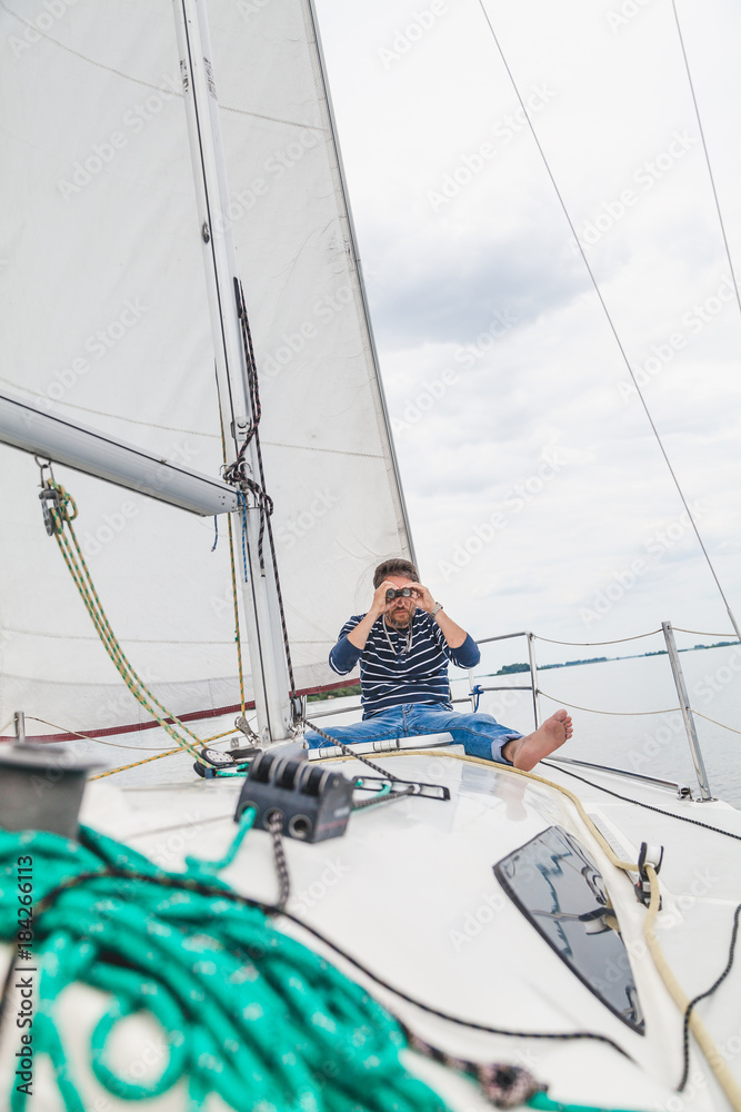 man sits on sailing yacht and looks through binoculars man sits on sailing yacht and looks through binoculars