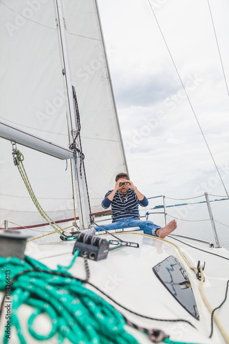 man sits on sailing yacht and looks through binoculars © glebchik