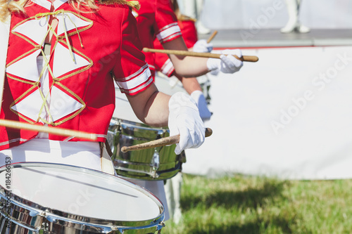 girl in red coat playing marching drum
