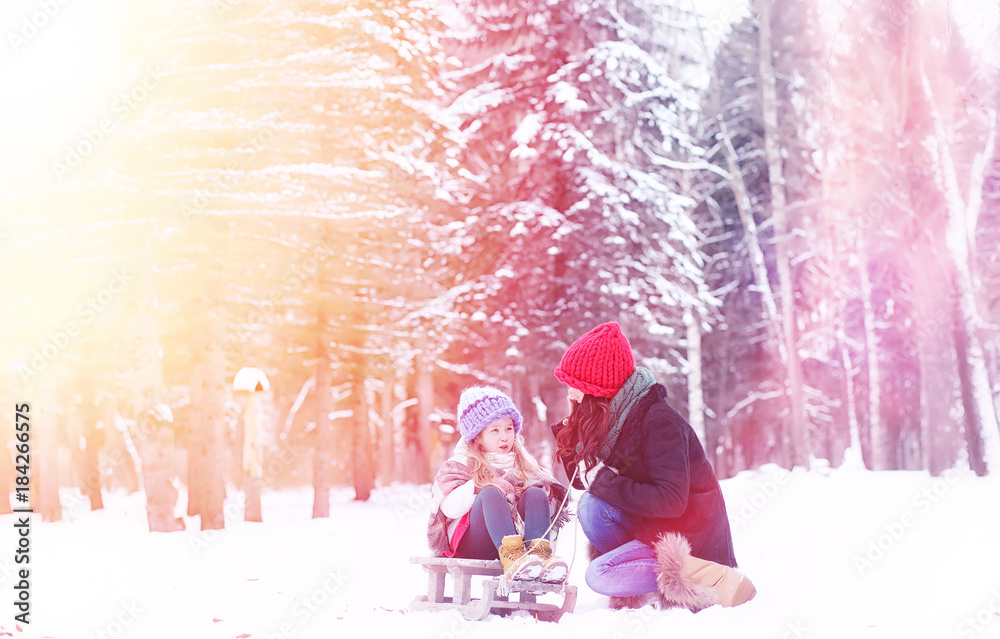 A winter fairy tale, a young mother and her daughter ride a sled A winter fairy tale, a young mother and her daughter ride a sled