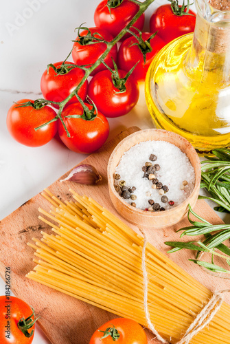 Italian food cooking, ingredients for preparation pasta spaghetti - tomato, garlic, olive oil, spices, white marble background, copy space