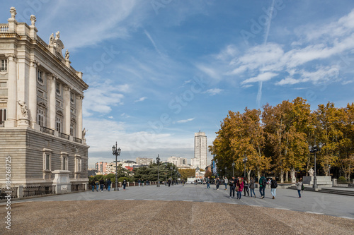 Facade of the Royal Palace of Madrid with tourists passing by its side