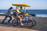 Friends riding on bicycle cart at seaside