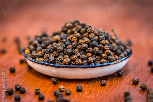Close up of raw black pepper,Piper nigrum  on wooden surface.