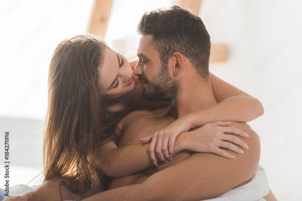 beautiful young woman embracing boyfriend from behind and kissing beautiful young woman embracing boyfriend from behind and kissing
