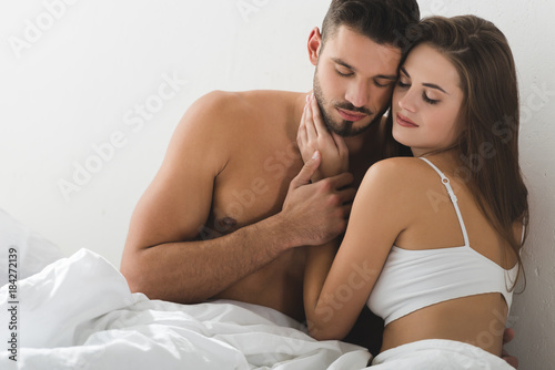 happy young couple cuddling in bed in morning