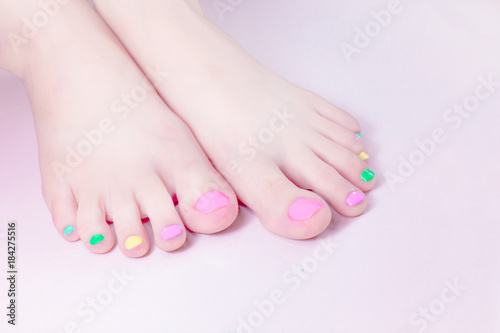 Woman painting toe nails own with manicure multi colored Nail Polish gel. fingernail paint,colorful in the bottle for beautiful feet . Customise sweet candy pastel bright colors tone .