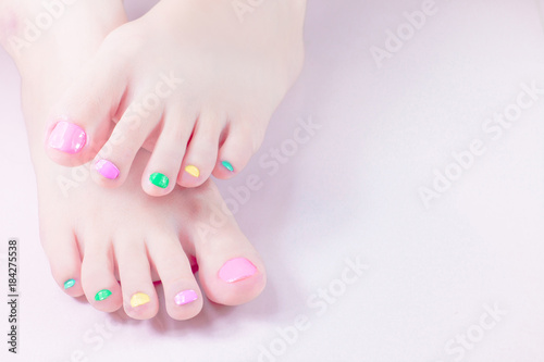 Woman painting toe nails own with manicure multi colored Nail Polish gel. fingernail paint colorful in the bottle for beautiful feet . Customise sweet candy pastel bright colors tone .