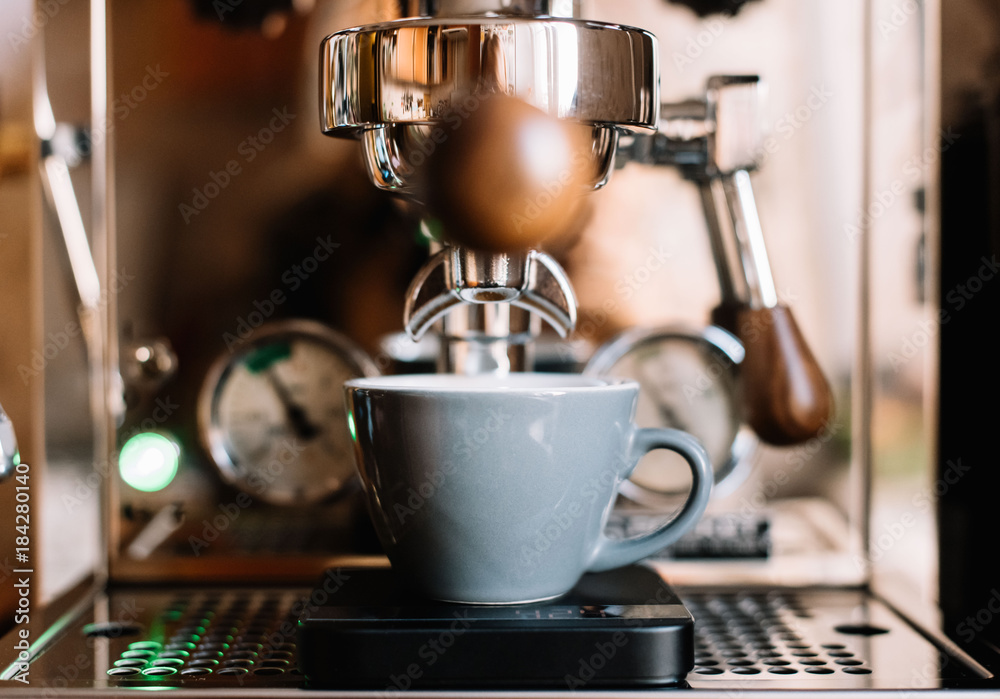 Delicious freshly ground morning coffee with a beautiful crema pouring into grey cup from espresso machine's portafilter, close up Delicious freshly ground morning coffee with a beautiful crema pouring into grey cup from espresso machine's portafilter, close up