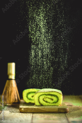 Matcha green tea cake and matcha green tea  powder flying  through the air