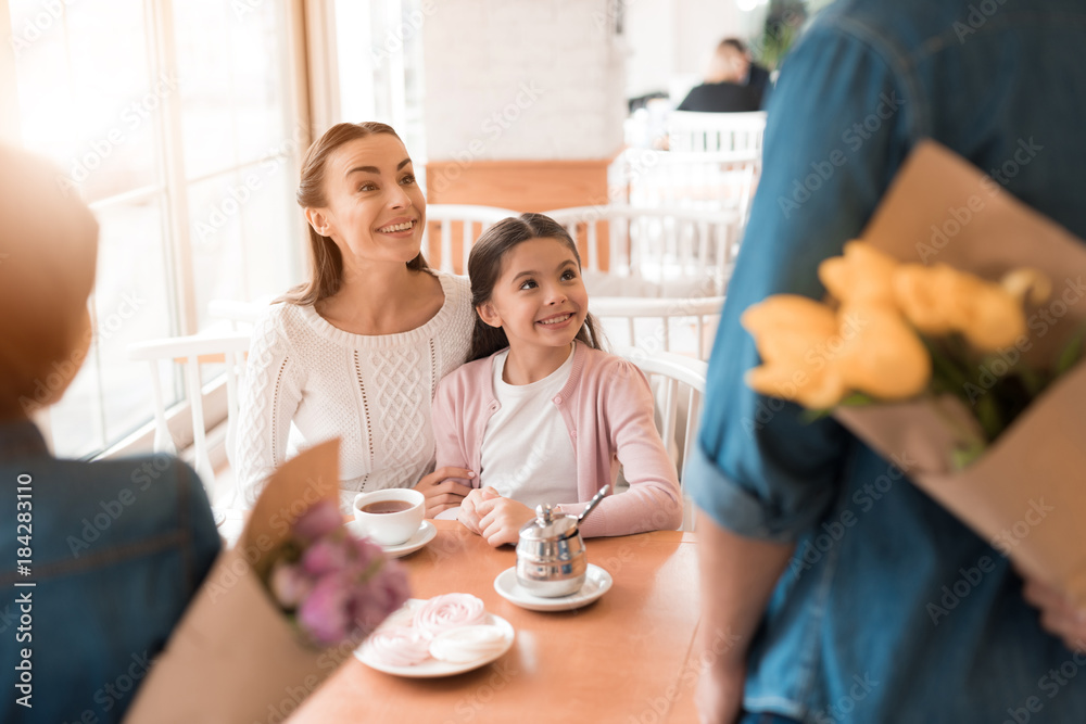 Dad and the little son are giving flowers to mother and daughter in a cafe. Dad and the little son are giving flowers to mother and daughter in a cafe.