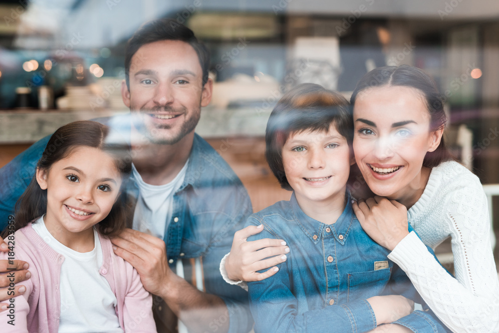 Obraz premium A young family are photographed through the glass in a cafe.
