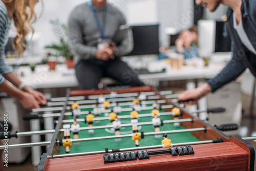 cropped image of people playing in table soccer at modern office