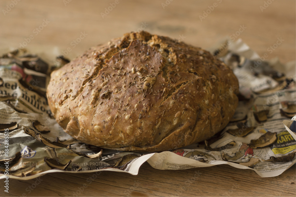 European cereal homemade loaf of bread on old newspapers with dried mushrooms