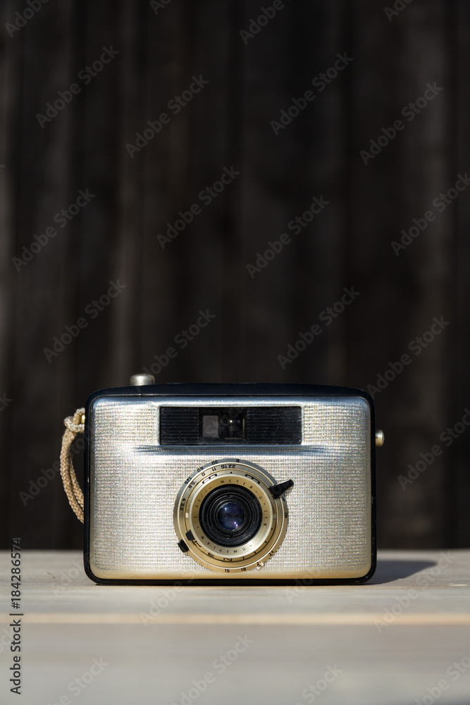Old vintage golden camera on wooden background 