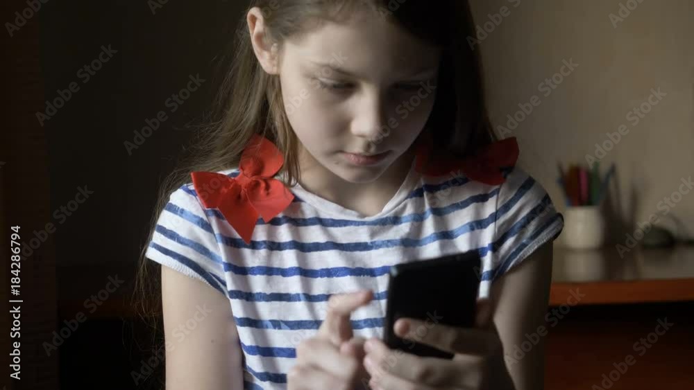 Smiling girl texting message on smartphone at home.