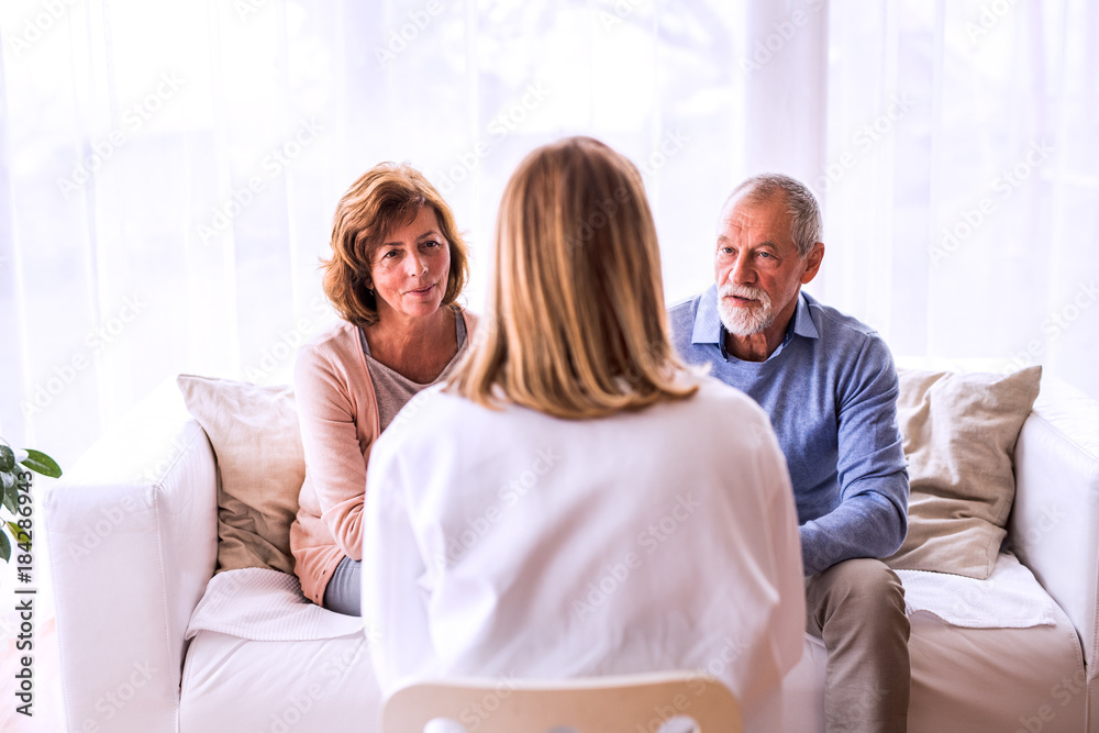 Obraz premium Female doctor talking to a senior couple.