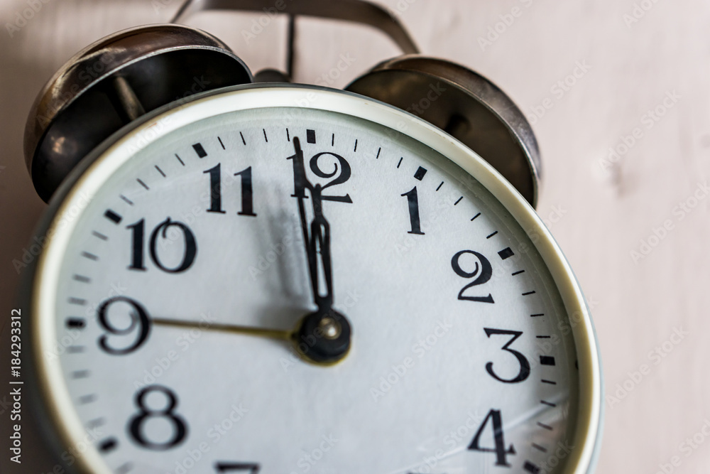A close-up of a clock showing 12.00 hours on rustick bacground. Concept New Year. A close-up of a clock showing 12.00 hours on rustick bacground. Concept New Year.