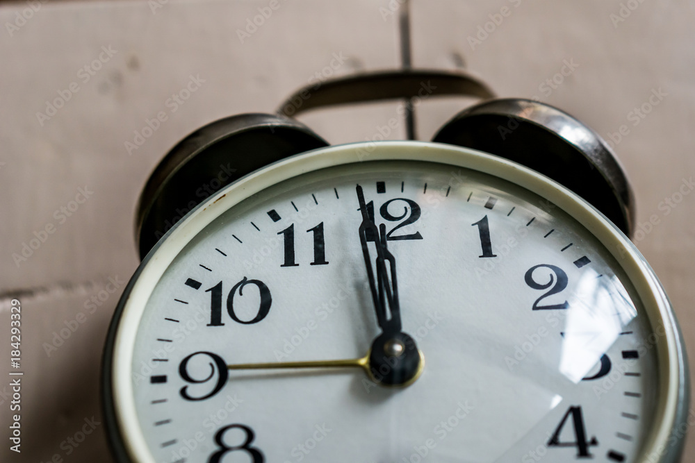 A close-up of a clock showing 12.00 hours on rustick bacground. Concept New Year. A close-up of a clock showing 12.00 hours on rustick bacground. Concept New Year.
