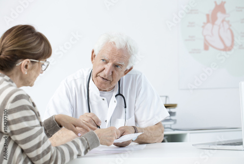 Elderly cardiologist consulting tests results