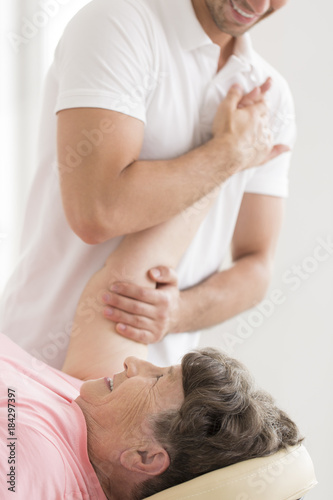 Obraz na plátně Physiotherapist stretching senior woman's shoulder